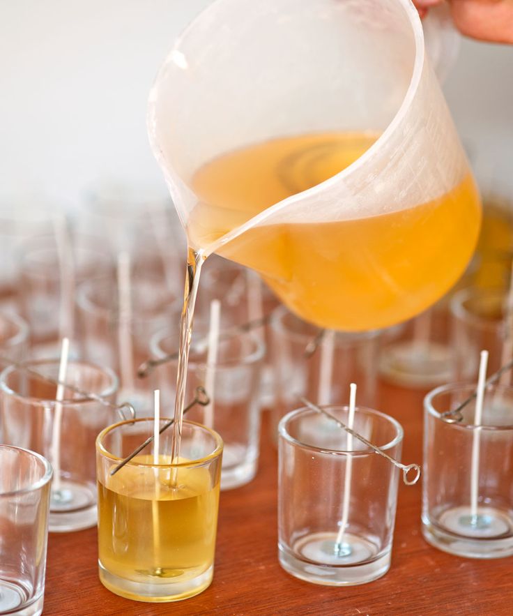 a person pours liquid from a pitcher into small glasses