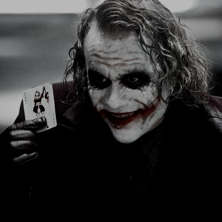 a man dressed as the joker holding a card