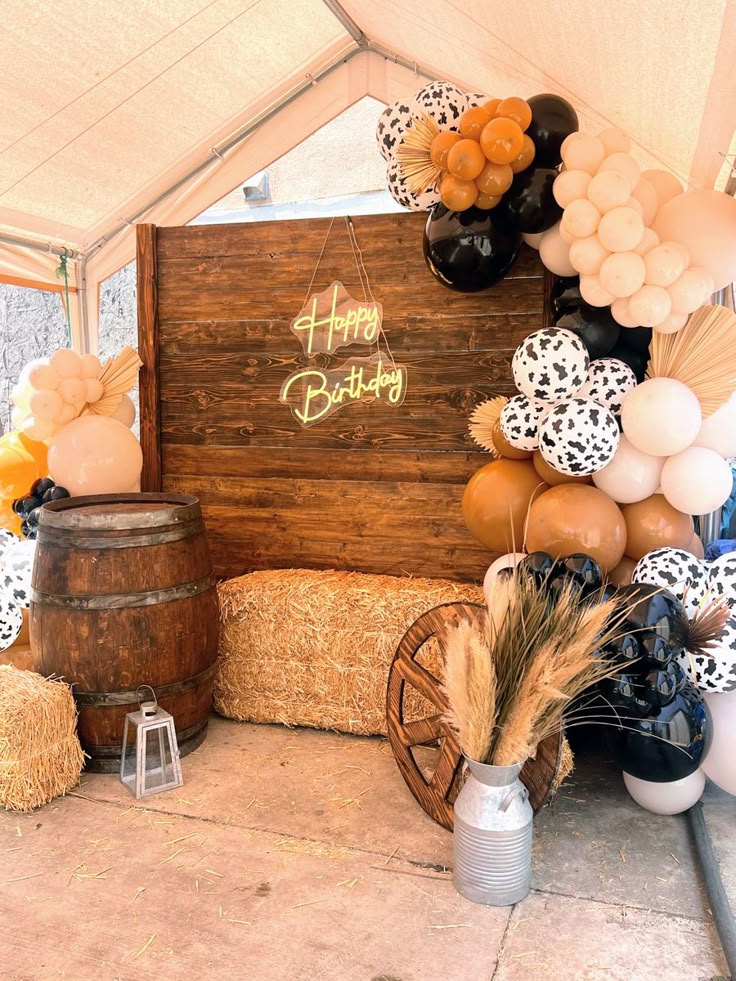 an outdoor birthday party with hay bales, balloons and other decorations on the ground