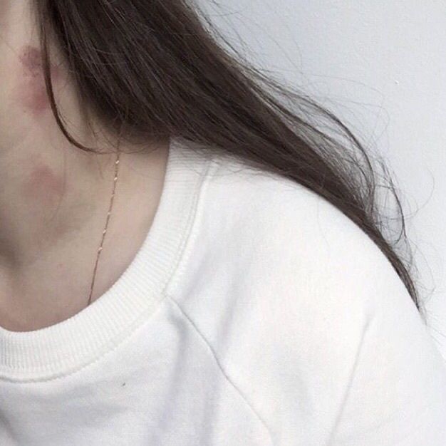 a close up of a person wearing a white shirt and holding a cell phone to their ear