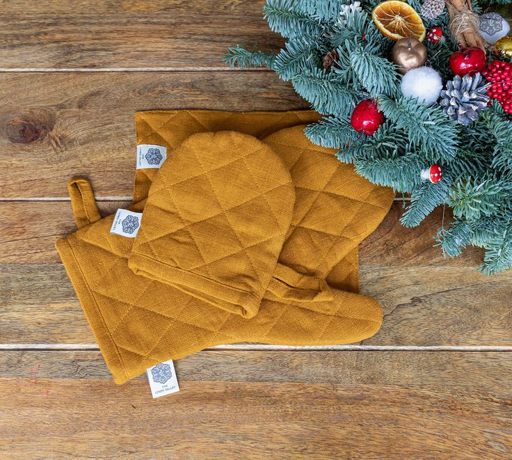 a pair of oven mitts sitting on top of a wooden floor next to a christmas tree