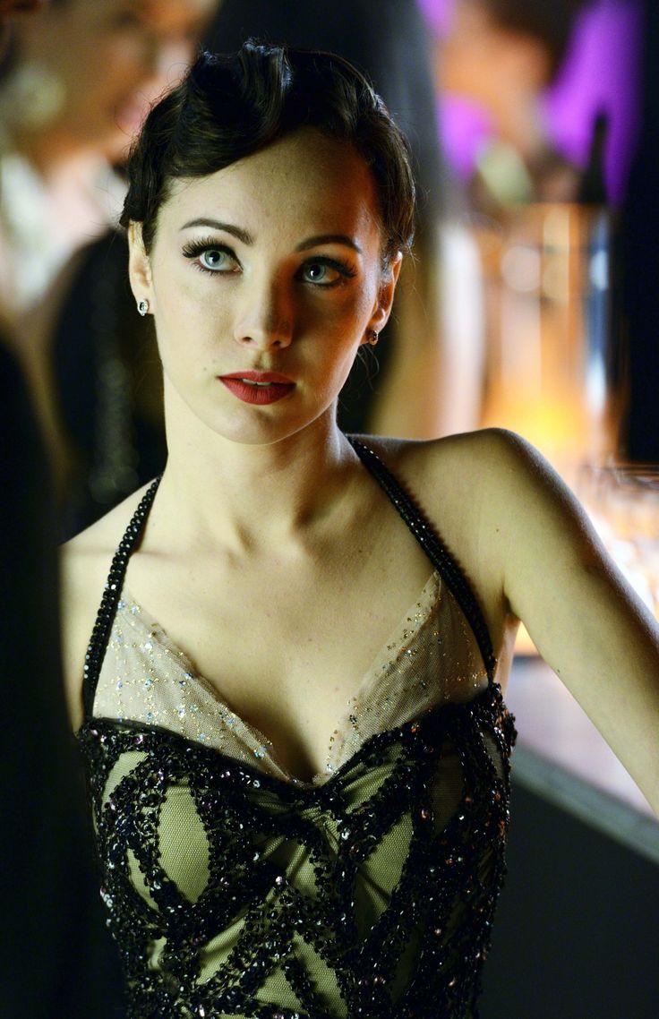 a woman wearing a black and white dress standing next to a glass filled with wine