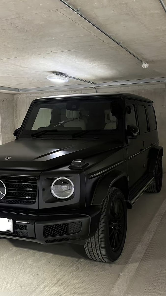 a black mercedes g - class parked in a parking garage with no one around it