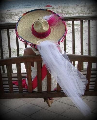 a woman wearing a straw hat on top of a wooden bench