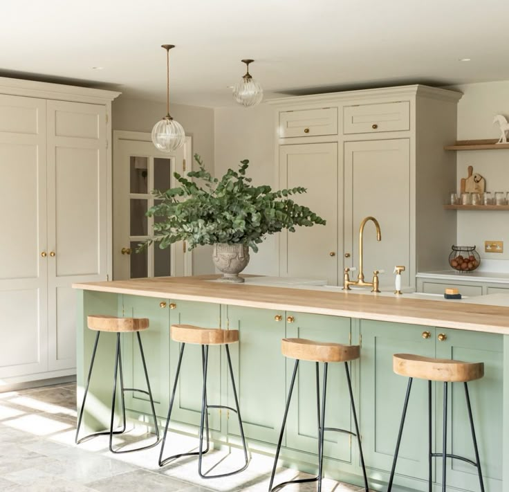 a kitchen with three stools in front of the counter and an island that has plants on it