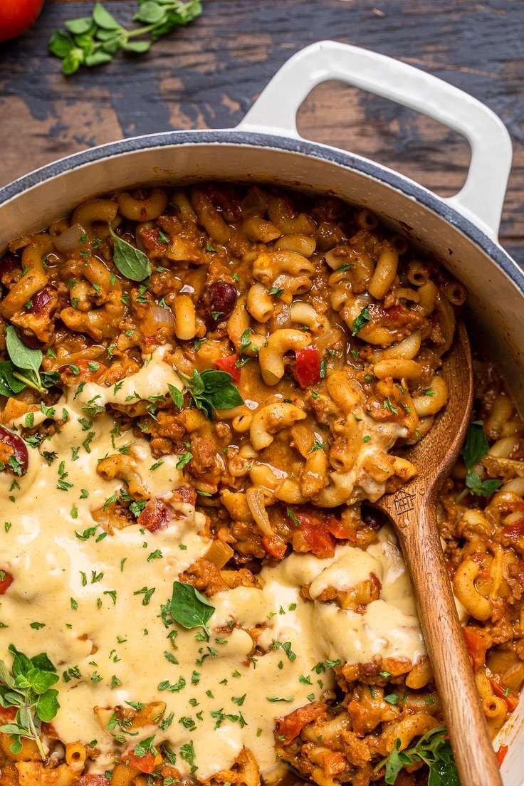 a pot filled with macaroni and cheese on top of a wooden table