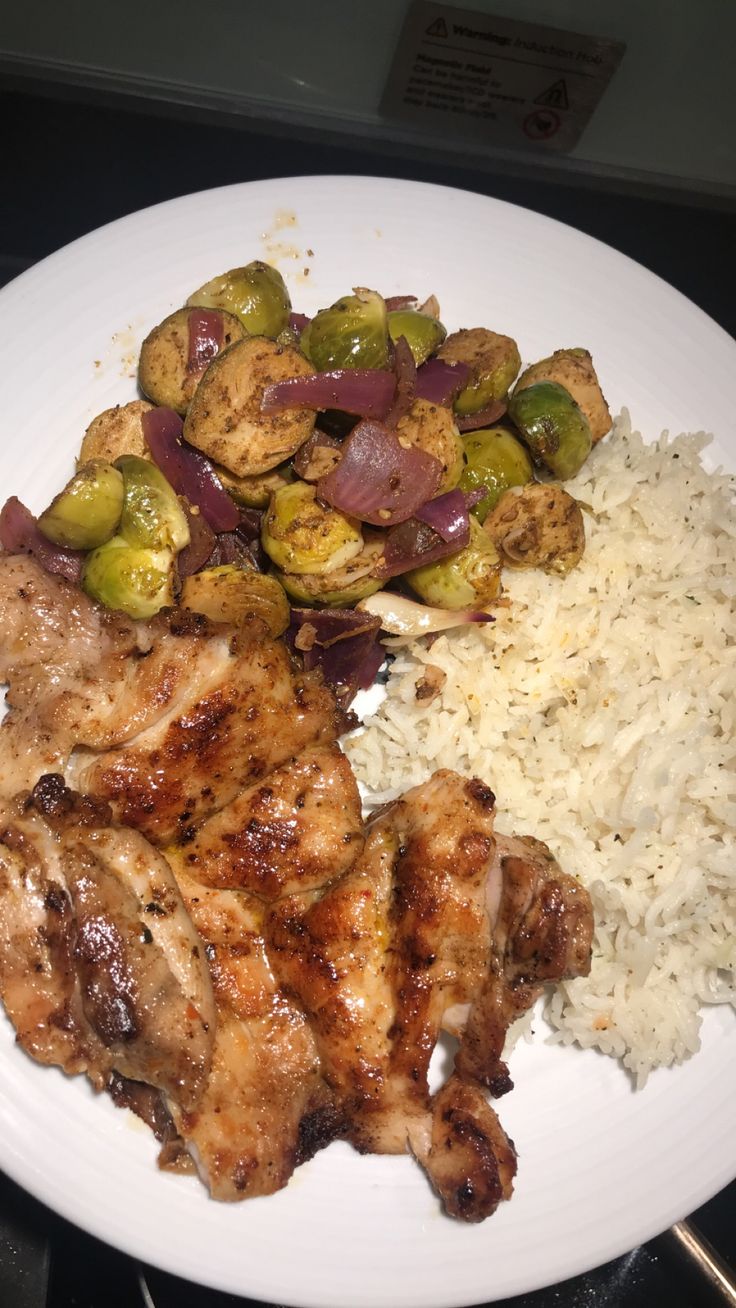 chicken, rice and brussel sprouts on a white plate