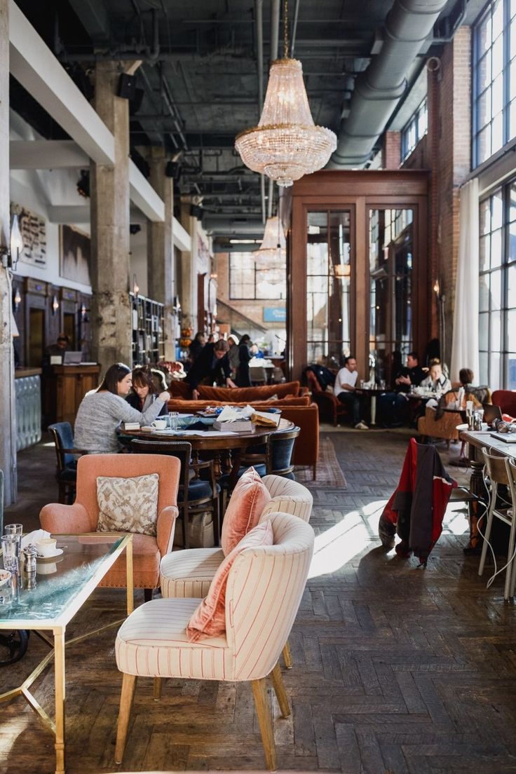 people are sitting at tables and eating in the dining room, with chandeliers hanging from the ceiling