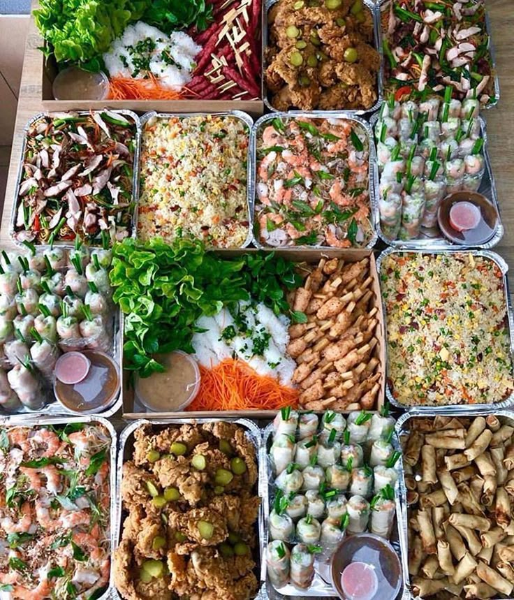 a table topped with lots of trays filled with different types of food and veggies