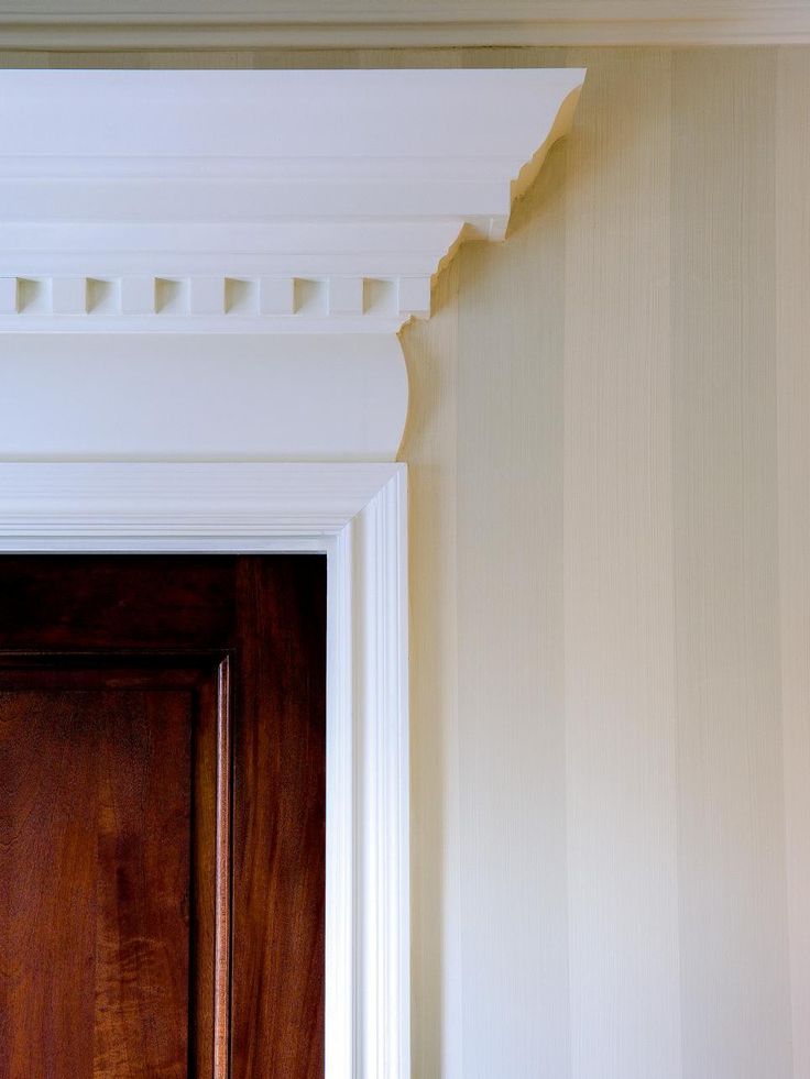 a wooden door in front of a wall with white molding on the walls and trim around it