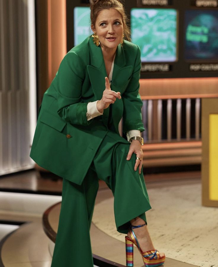 a woman sitting on top of a table wearing green pants and high heeled shoes