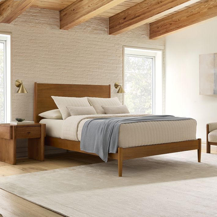 a bed sitting in a bedroom next to two chairs and a table on top of a rug