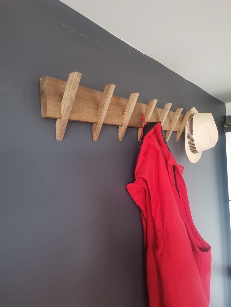 a coat rack and hat hanger on the wall next to a red hoodie