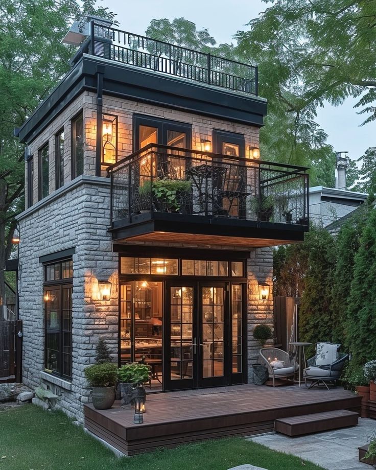 a house that is sitting in the grass with lights on and stairs leading to it