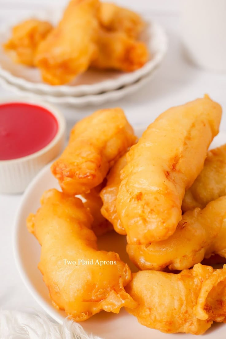 some fried food on a white plate next to sauces and condiments for dipping