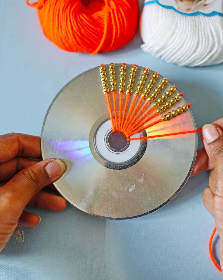 a person is holding a cd in front of several balls of yarn and knitting needles