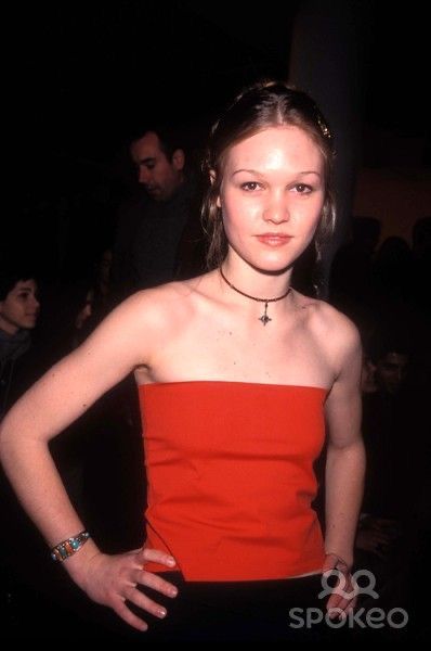 a young woman in an orange strapless dress posing for the camera with her hands on her hips