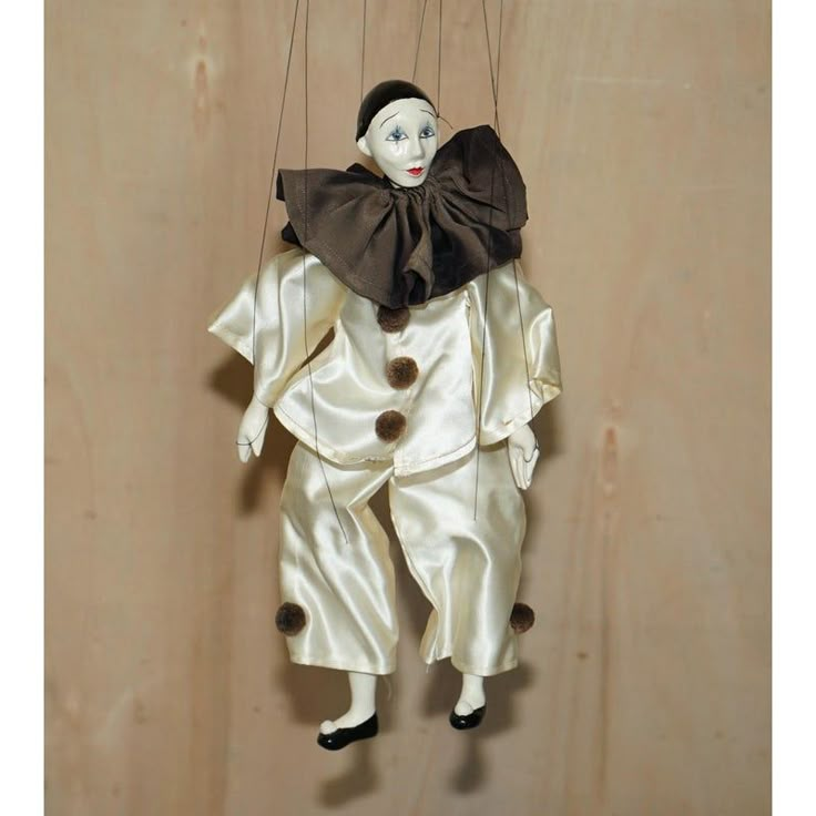 a doll hanging from strings on a wooden wall