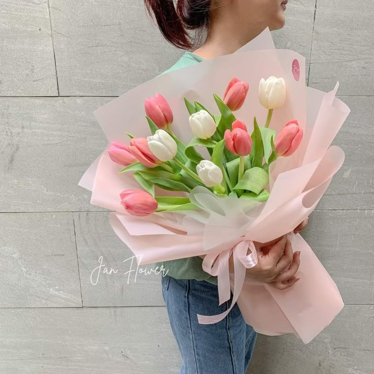 a woman holding a bouquet of pink and white tulips