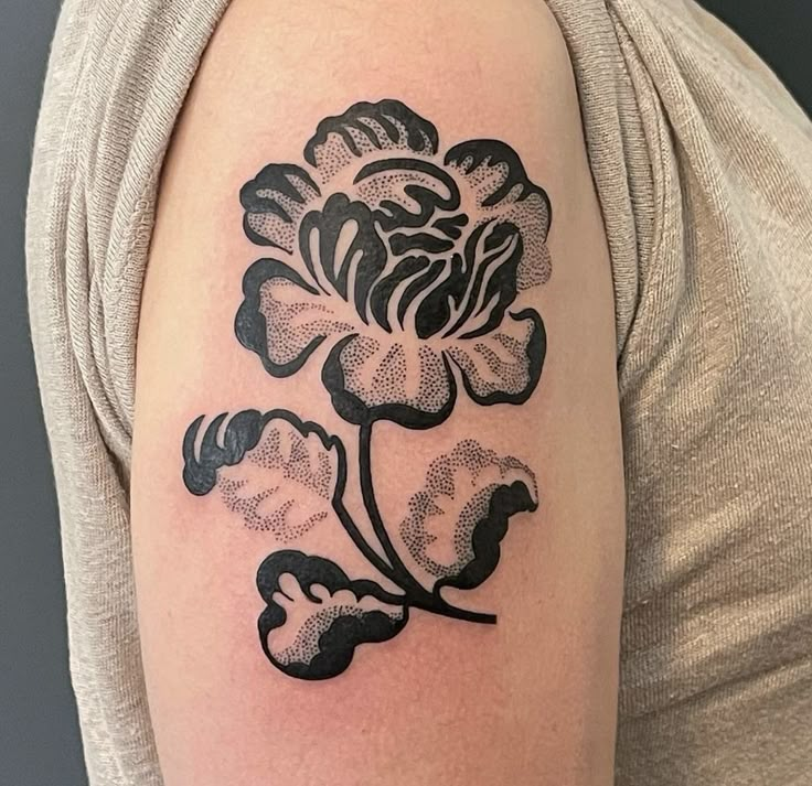 a black and white flower tattoo on the left upper half of the arm, with three petals