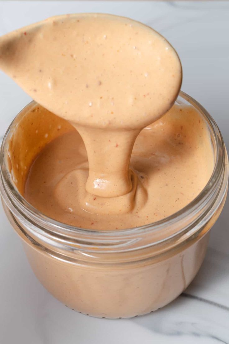 a spoon full of peanut butter on top of a jar