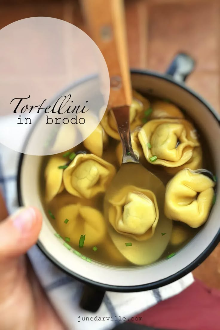 dumplings in broth are being cooked in a pot with a wooden ladle