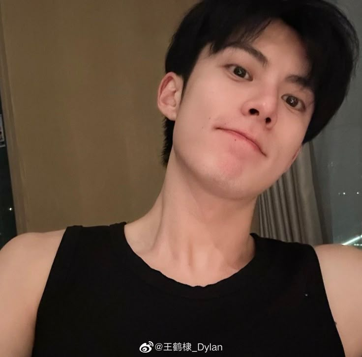 a young man with black hair is taking a selfie