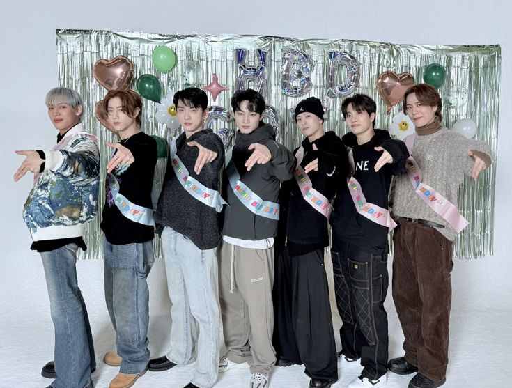 a group of young men standing next to each other in front of a party backdrop