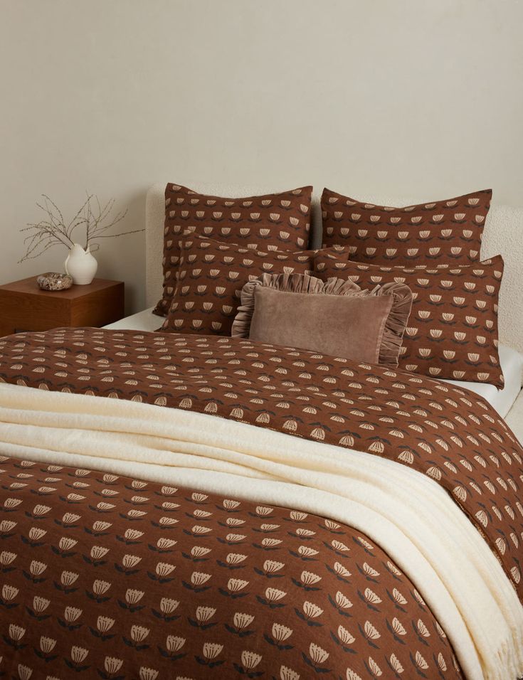 a bed with brown and white bedspread and pillows