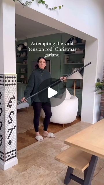 a woman standing in front of a table holding a broom with the caption attempting the visual tension rod christmas garland