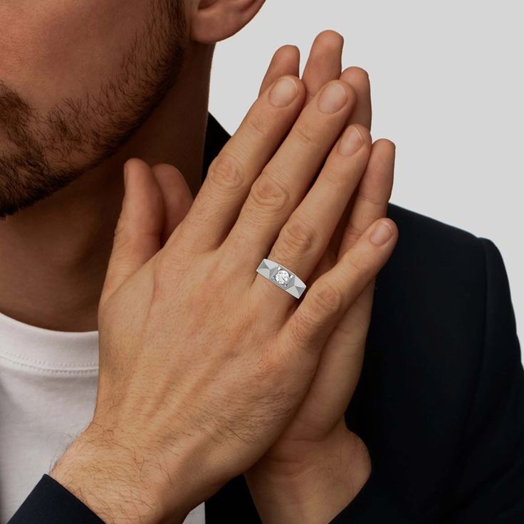 a man wearing a white gold wedding band and holding his hands in front of his face