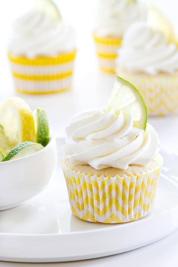 cupcakes with white frosting, lime and lemon wedges on the side