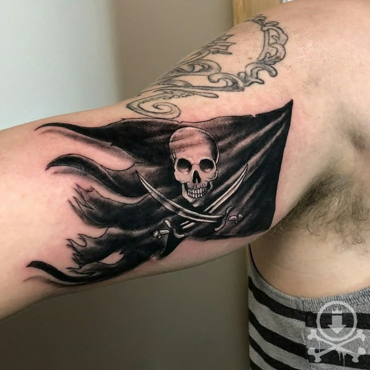 a man's arm with a pirate flag tattoo on it and a skull in the middle