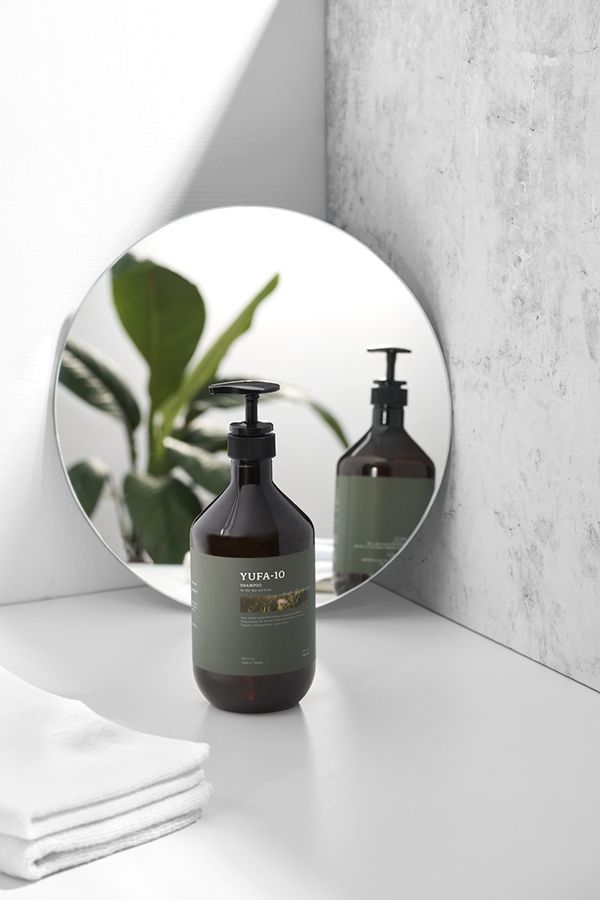 a mirror sitting on top of a white counter next to a bottle of lotion