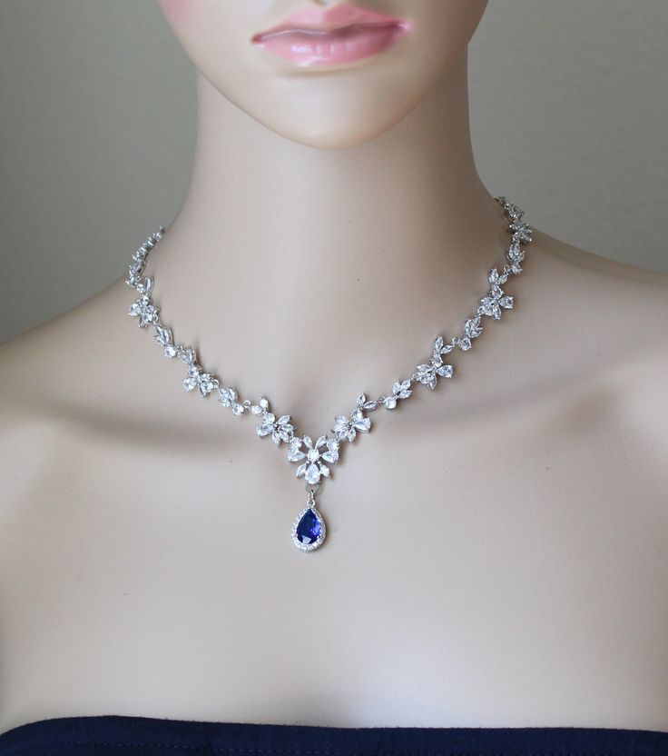 a woman's head wearing a blue dress with a necklace and earrings on it