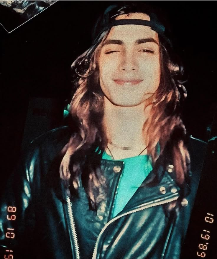 a young man with long hair wearing a leather jacket