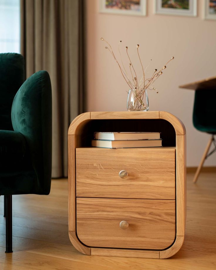 a wooden table with two drawers in front of a chair and pictures on the wall