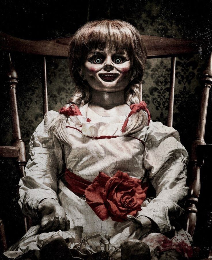 a creepy doll sitting in a chair with a red rose on it's lap