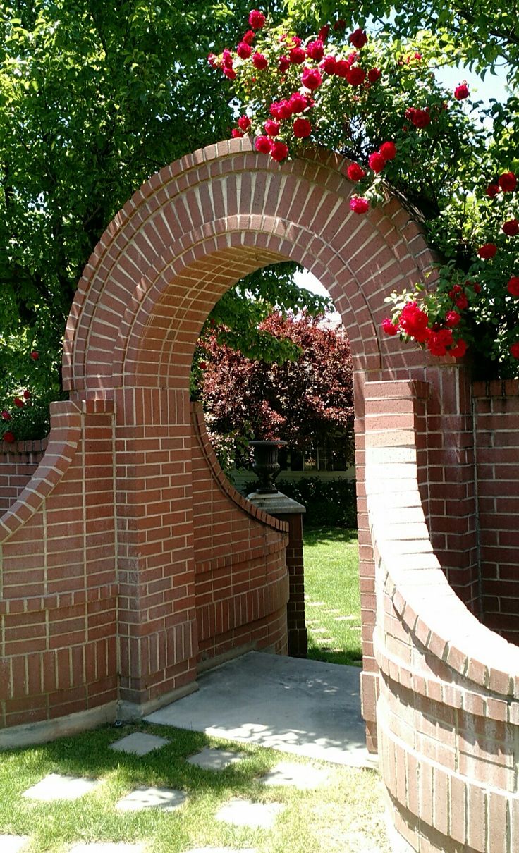 a brick archway with flowers growing over it