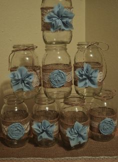 there are many glass jars with blue flowers on the lids and ribbons in each jar