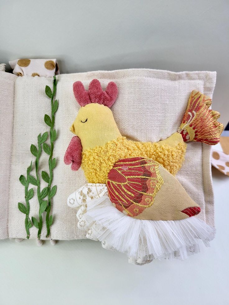 a close up of a piece of cloth with a chicken on it and green plants