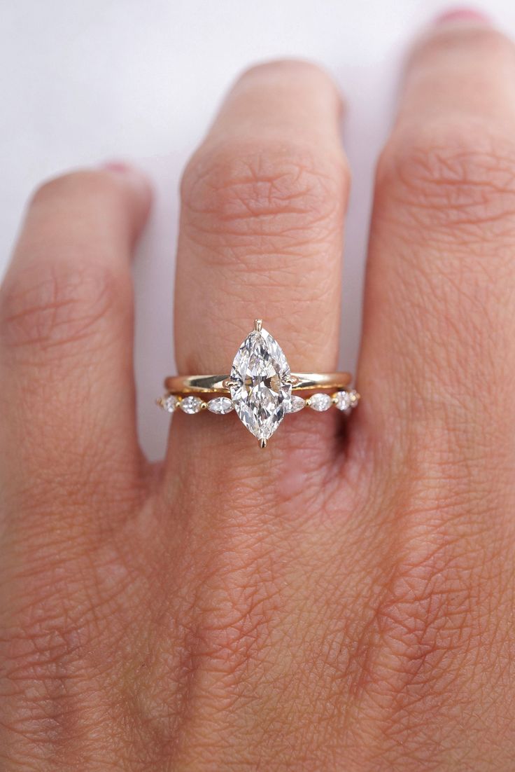 a woman's hand with a diamond ring on top of her finger and an engagement band