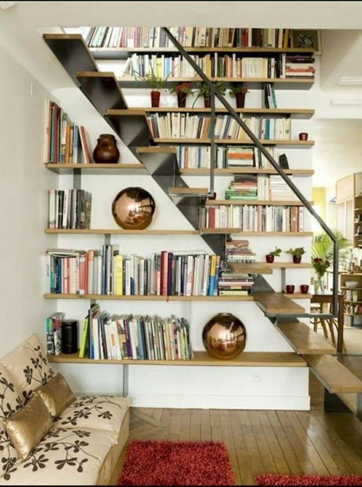 a man sitting on top of a stair case next to a book shelf filled with books