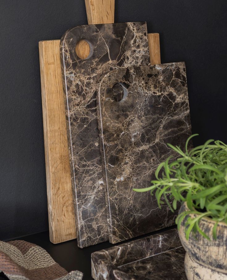 a black marble cutting board sitting next to a potted plant