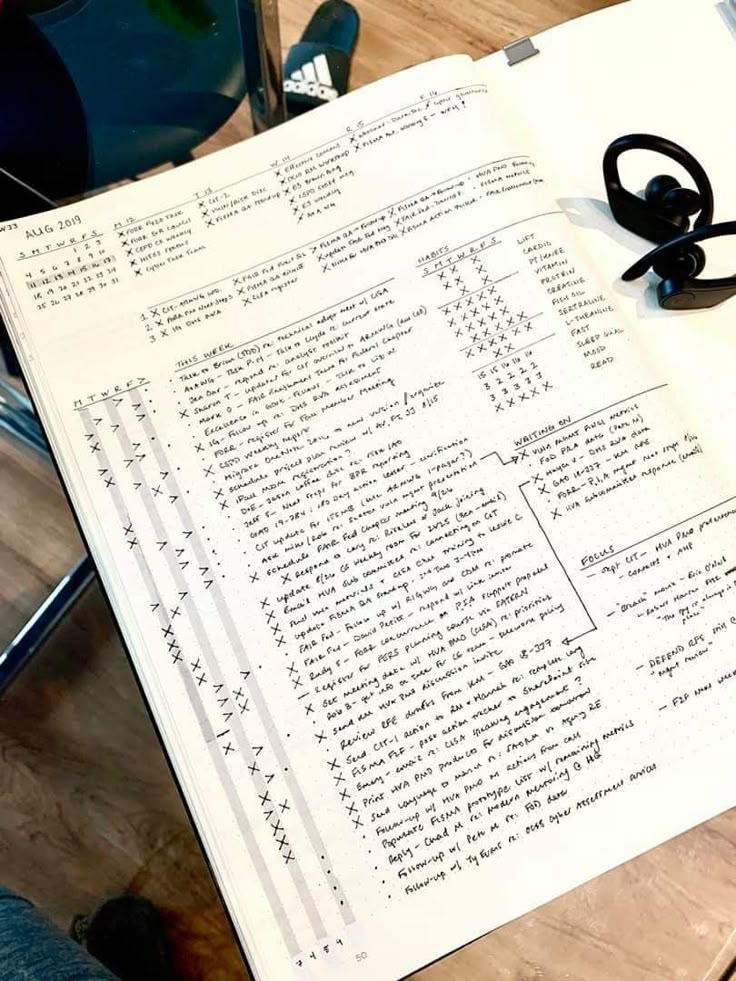 an open book sitting on top of a wooden table next to a pair of headphones