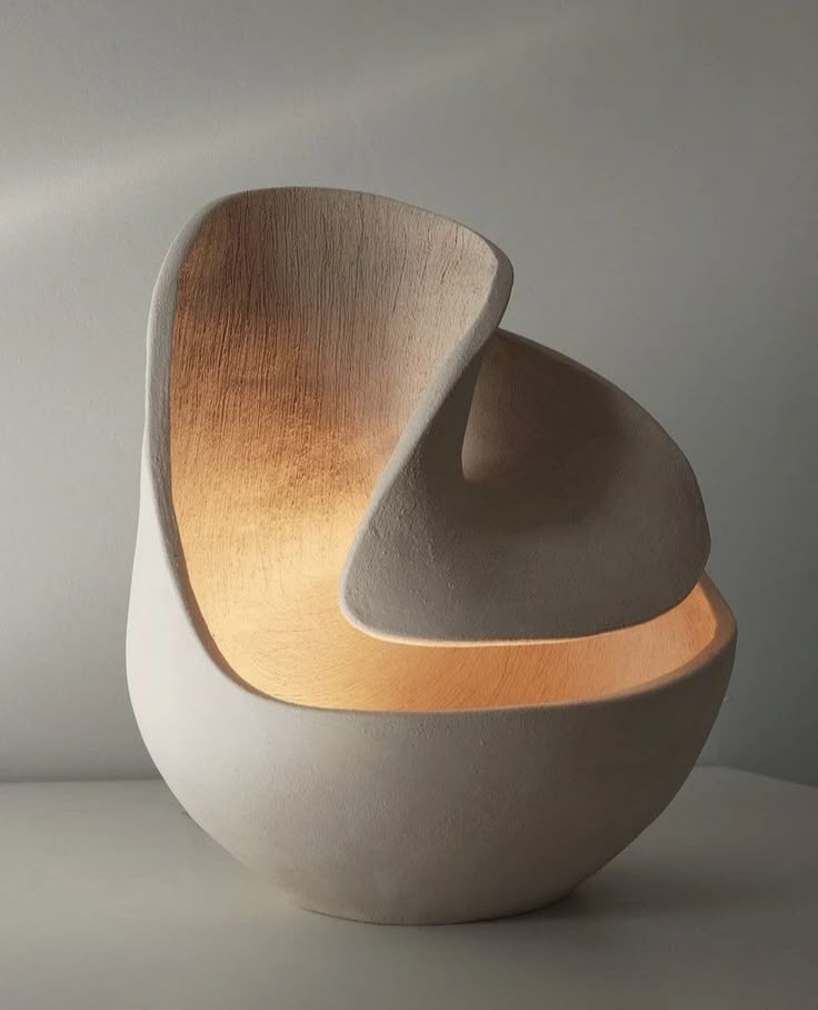 two white bowls sitting next to each other on top of a table with light coming from them