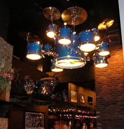 a blue drum set hanging from the ceiling in a room with brick walls and lights