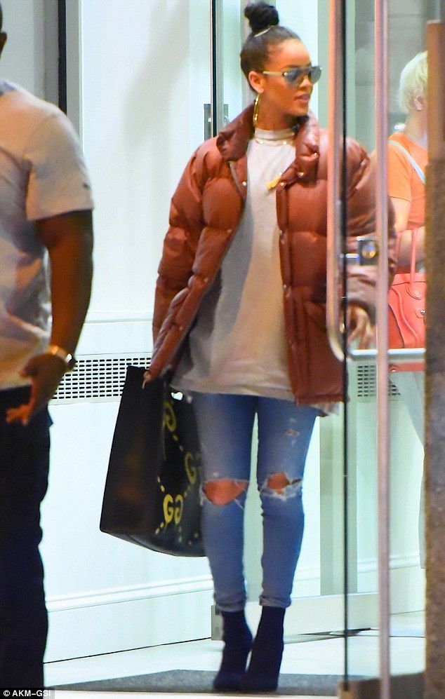 a woman in ripped jeans and a puffy jacket is seen walking through an airport