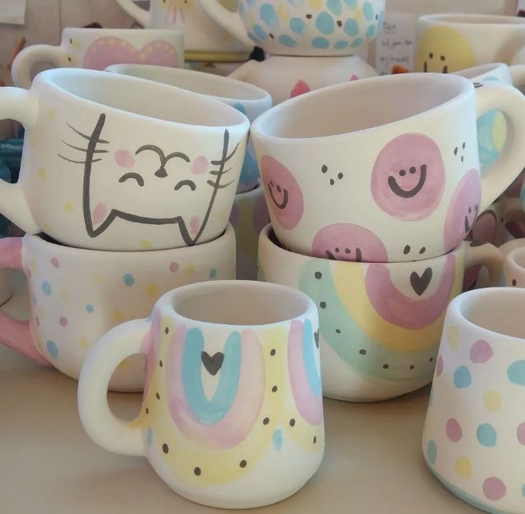 many cups with faces painted on them are stacked up in the shape of hearts and cats