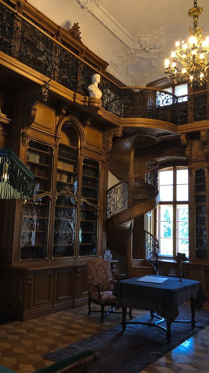 a room with many bookshelves and chandeliers on the ceiling, along with a table in front of it